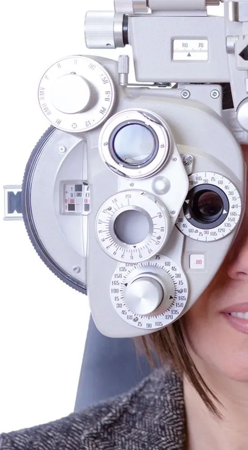 A woman is sitting in front of an eye exam machine.