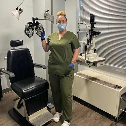 A woman in green scrubs holding up an eye exam.