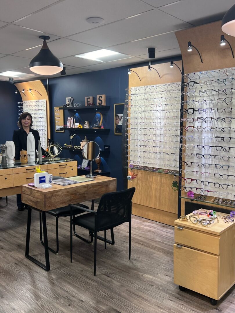 A woman is sitting at the counter of an optometry office.